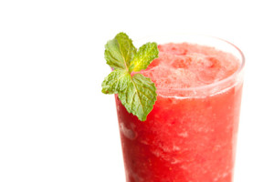 Red fruit flavored frozen cocktail or smoothie beverage with straw and stirring stick.